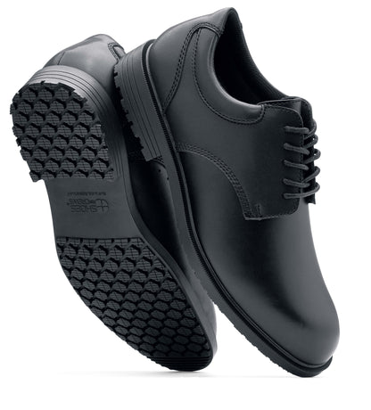 The Shoes for Crews Cambridge III is a slip-resistant leather dress shoe, with removable cushioned insoles and a padded comfort collar, pair viewed vertically, with a focus on the sole and side.